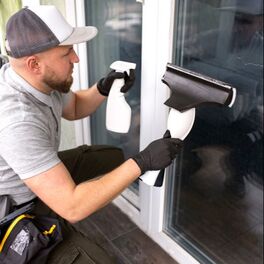 Professional cleaning technician preparing a home window before residential window tinting installation